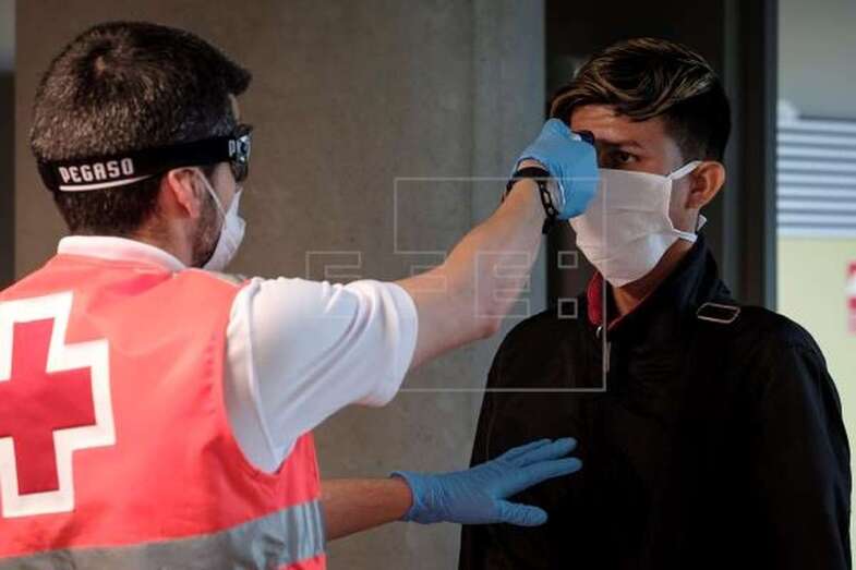 Personal de Cruz Roja tomando la temperatura a los pasajeros a su llegada a Gran Canaria (Foto EFE / Ángel Medina G.)